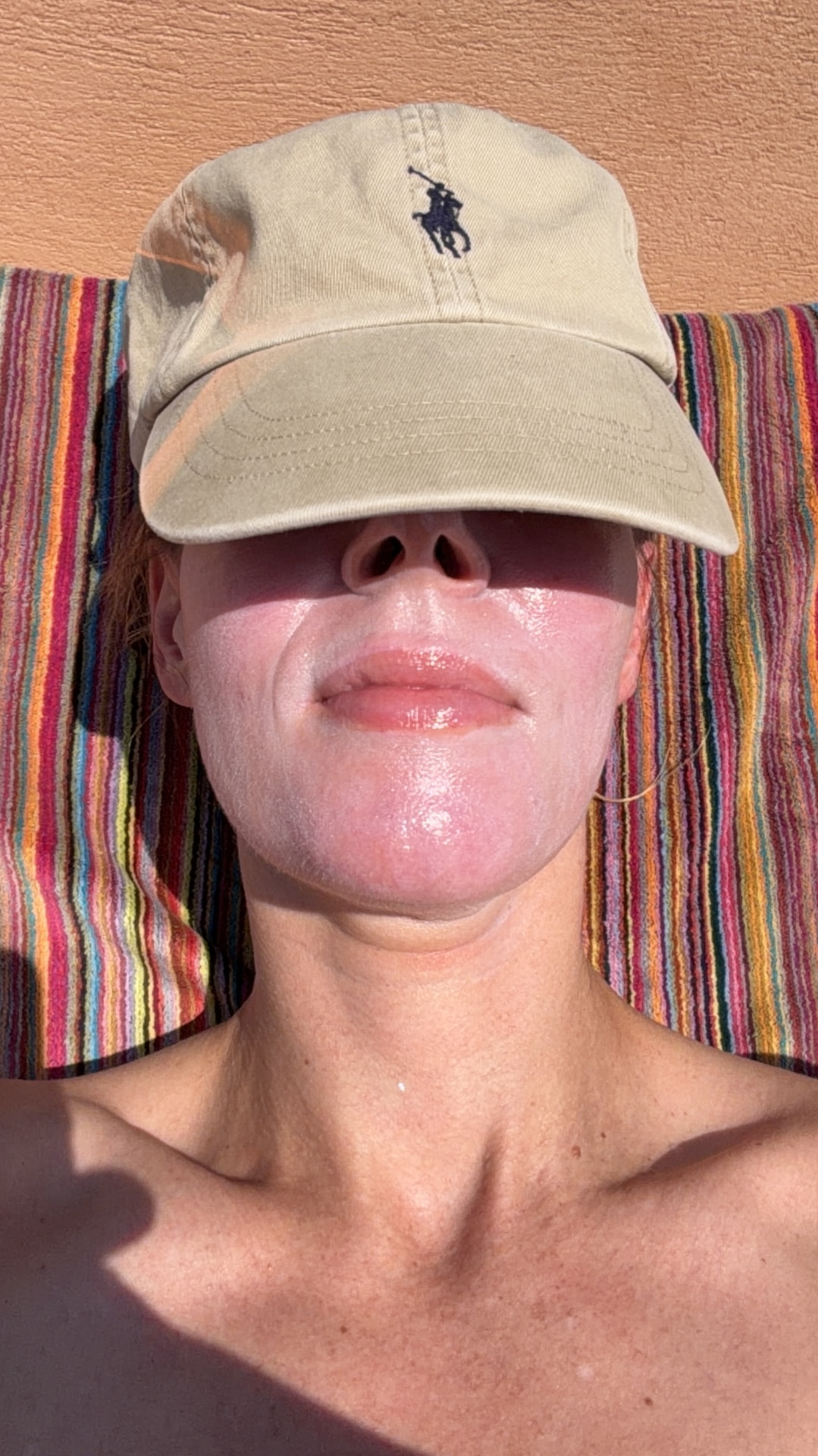 Élise lying in the sun with a thick layer of mineral sunscreen across her nose and cheeks, a cap pulled low over her eyes